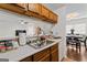 An open kitchen featuring wood cabinets, a stainless steel sink, and a view into the living and dining areas at 555 Windchase Ln, Stone Mountain, GA 30083