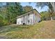 Rear exterior view of the white brick home on a lot with mature trees, showcasing its spacious backyard at 256 Butterworth Rd, Canton, GA 30114