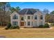 Beautiful two-story brick home featuring many windows, a turret, and a circular driveway on a treed lot at 1202 Persimmon Way, Mcdonough, GA 30252