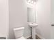 A half bathroom featuring a pedestal sink, toilet, modern mirror, and new fixtures at 8516 (Lot 130) Polston Place Dr, Douglasville, GA 30134