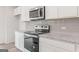 Stylish kitchen features stainless steel appliances, modern backsplash, granite countertops, and white cabinets at 8516 (Lot 130) Polston Place Dr, Douglasville, GA 30134