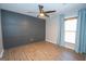 Bedroom with wood floors, a paneled accent wall, and a window with light blue curtains at 100 Lanyard Bnd, Peachtree City, GA 30269