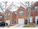 View of a brick townhome with a single car garage, well manicured lawn, and minimal winter foliage at 6517 Snowbird Ln, Douglasville, GA 30134
