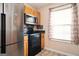 Kitchen showcasing stainless steel refrigerator, black appliances and a window with floral curtains at 6517 Snowbird Ln, Douglasville, GA 30134