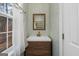 Stylish bathroom with wood vanity, brass fixtures, and decorative wallpaper at 9209 W Banks Mill Rd, Winston, GA 30187