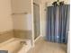 Neutral bathroom showcasing a tub with tile surround and glass-enclosed shower with blue curtains at 4019 Pin Oak Trl, Decatur, GA 30034
