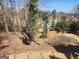 View of backyard with lawn and tiered retaining walls surrounded by bare trees at 718 Avalon Way, Peachtree City, GA 30269