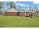 Spacious backyard with lush green grass and the rear of the red brick home featuring a wood deck at 81 Bowers Rd, Moreland, GA 30259