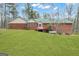 Expansive backyard with lush green grass and the rear of the red brick home featuring a wood deck at 81 Bowers Rd, Moreland, GA 30259
