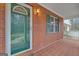 Close-up of a brick-paved porch featuring a green front door, decorative shutters, and outdoor lighting at 81 Bowers Rd, Moreland, GA 30259
