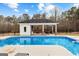 A refreshing backyard pool featuring a modern outdoor kitchen and lounge area, surrounded by lush greenery at 203 Shelby Ln, Fayetteville, GA 30215