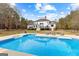 Stunning backyard pool with lounge chairs, steps, and deck, set against a backdrop of lush trees and blue skies at 203 Shelby Ln, Fayetteville, GA 30215