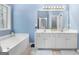 Bathroom featuring dual sinks, a large mirror and a soaking tub at 306 Interlake Pass, Mcdonough, GA 30252