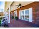 Covered porch featuring white columns and brick flooring, complemented by lush green plants and a front door at 111 Dixson Rd, Bowdon, GA 30108