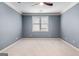 Simple bedroom featuring plush carpet, light blue paint, a ceiling fan, and a large window at 103 Augusta Dr, Peachtree City, GA 30269