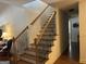 Bright staircase featuring a light wood rail, black metal spindles, and hardwood floors leading to the upper level at 101 Deer Park Dr, Carrollton, GA 30116