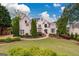 Beautiful two-story home with lush landscaping, a green lawn, mature trees, and a welcoming facade at 675 Falls Lake Dr, Alpharetta, GA 30022