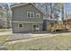 Backyard view of gray siding, deck with stairs, and a concrete patio with a gravel area at 1967 Levgard Ln, Riverdale, GA 30296
