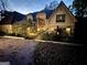 Well-lit home exterior at dusk with a brick driveway and lush greenery at 275 Old Mill Ct, Fayetteville, GA 30214