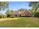 Traditional brick home featuring a well-manicured lawn, mature trees, and classic architectural details at 830 Streamside Dr, Mcdonough, GA 30252