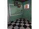 View of a room with black and white tiled floors, mint green paneled walls, and small window at 953 South Ave, Forest Park, GA 30297