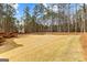 Expansive backyard with grass and treeline, features a wooden deck and stairs leading to the home at 115 Wellborn Chase, Fayetteville, GA 30215