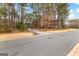 Image features a street view with a glimpse of the driveway and mailbox of a home amidst a wooded setting at 115 Wellborn Chase, Fayetteville, GA 30215