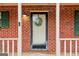 Close-up of a charming front porch with a wreath-adorned door, green shutters, and white columns at 979 Walnut Creek Ln, Jonesboro, GA 30238