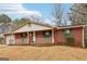 Cozy front porch of a brick home with green shutters, white porch railings, and a decorative wreath on the front door at 979 Walnut Creek Ln, Jonesboro, GA 30238