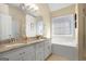 Bright bathroom featuring double sinks, granite countertops, a tub, and a large vanity mirror at 1421 Saint Charles Ct, Conyers, GA 30094