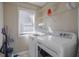 Laundry room with washer, dryer, shelving, and natural light from a bright window at 1421 Saint Charles Ct, Conyers, GA 30094