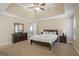 Spacious main bedroom featuring tray ceilings, ceiling fan, carpeted floors, and a large wooden dresser at 1421 Saint Charles Ct, Conyers, GA 30094