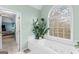 Well-lit bathroom showing a soaking tub, a large window, and decorative plants at 220 Terrane Rdg, Peachtree City, GA 30269