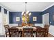 Formal dining room with a large wooden table, elegant chandelier, and blue accent wall perfect for entertaining guests at 220 Terrane Rdg, Peachtree City, GA 30269
