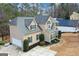 A tan two-story home with a gray roof featuring lush landscaping, a side-entry garage, and mature trees at 220 Terrane Rdg, Peachtree City, GA 30269