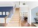 Grand staircase with hardwood floors and patterned carpet leads to a spacious landing, offering a glimpse of the living room at 220 Terrane Rdg, Peachtree City, GA 30269