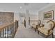 Upstairs hallway featuring carpet, stone accent wall, with two chairs and a view to the bathroom at 804 Carnellian Ln, Peachtree City, GA 30269