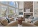 Cozy living room featuring a stone fireplace, large windows, and neutral decor at 804 Carnellian Ln, Peachtree City, GA 30269