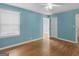 Bedroom showing a ceiling fan, hardwood floors, a light blue wall and an open doorway at 6393 Walker Rd, Riverdale, GA 30296