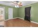 Bedroom with hardwood floors, white trim, ceiling fan, and bright green walls at 6393 Walker Rd, Riverdale, GA 30296