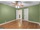 Bedroom has a ceiling fan, hardwood floors, light green walls, and an open doorway at 6393 Walker Rd, Riverdale, GA 30296