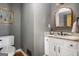 Stylish half bathroom with a decorative mirror, marble countertop vanity, and modern fixtures, accented by grey wall paint at 302 Cumberland Ct, Peachtree City, GA 30269