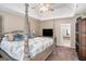 Inviting main bedroom with four-poster bed, tray ceiling, TV, and ensuite bath access at 302 Cumberland Ct, Peachtree City, GA 30269