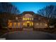 Elegant two-story home featuring a grand entrance, manicured landscaping, and a circular driveway at twilight at 300 Annelise Park Dr, Fayetteville, GA 30214