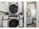 Modern laundry room featuring stacked washer and dryer with white cabinets and laundry sink at 300 Annelise Park Dr, Fayetteville, GA 30214