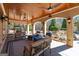 Expansive covered patio with ceiling fans, stone flooring, and cozy seating area overlooks the landscaped backyard and pool at 300 Annelise Park Dr, Fayetteville, GA 30214