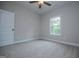 A simple bedroom with neutral walls, plush carpet, a ceiling fan, a window, and an interior closet at 3264 Greenhill Ct, Villa Rica, GA 30180