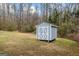 Outdoor shed with double doors offers extra storage space in a wooded backyard at 10 Allen Oaks Way, Covington, GA 30016