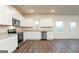 Bright kitchen featuring stainless steel appliances, white cabinets, and wood-look floors at 1041 Claas Way, Locust Grove, GA 30248