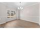 Inviting dining room with elegant chair rail, wood-look flooring, a modern chandelier, and large window views at 135 Weeping Willow Way, Tyrone, GA 30290